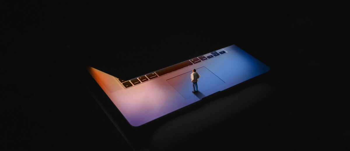 Illustration of a miniature human standing in an opening laptop with a colorful glowing screen